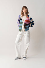 Front full body perspective of woman in all white, modelling our multi-coloured cashmere v neck cardigan