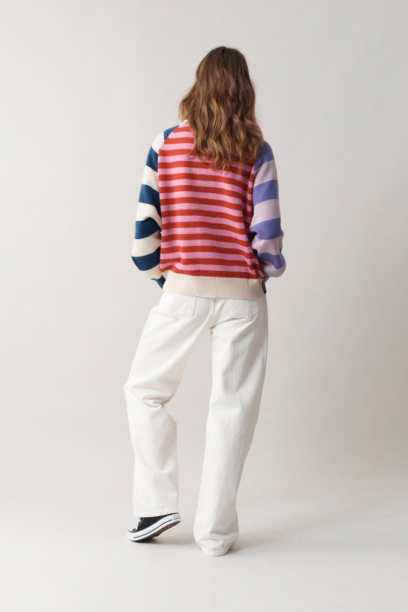 Rear full body perspective of woman in all white, modelling our multi-coloured cashmere v neck cardigan